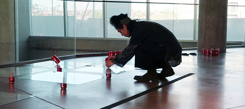 Photo of artist Jaejoon Jang placing cans of Coca-Cola over and under sheets of glass