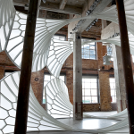 A light, airy, cathedral-like structure installed in a tall industrial space.