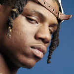 Image: Detail of a close-up portrait of Kane Wave, a hip hop artist from Buffalo, NY; Wave wears a backwards ball cap and is photographed giving the camera a side-long glance