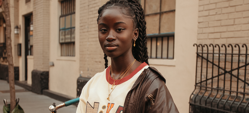 Image: Beautiful dark-skinned woman photographed in an urban environment with gold color tones bouncing throughout the image.