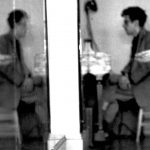 Image: Detail of a black and white photograph by Robert Rauschenberg of an individual at a piano and a crouched dancer who balances on his toes with his arms outstretched; his image is reflected back to him in a dance studio mirror.