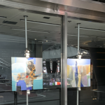 Image: Art on the Avenue signage and artworks on display behind a glass storefront.