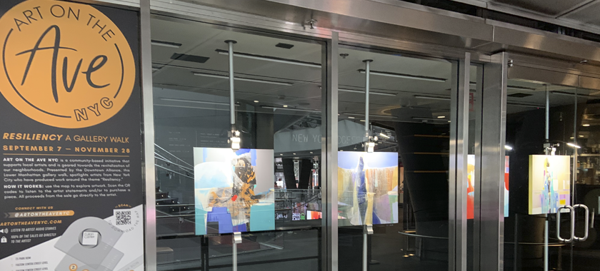 Image: Art on the Avenue signage and artworks on display behind a glass storefront.