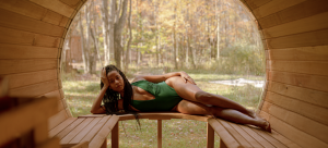 Image Detail: Photo of an artist lying on their side in a bathing suit, relaxing in a sauna as part of Activation Residency's "Respite as Resistance."