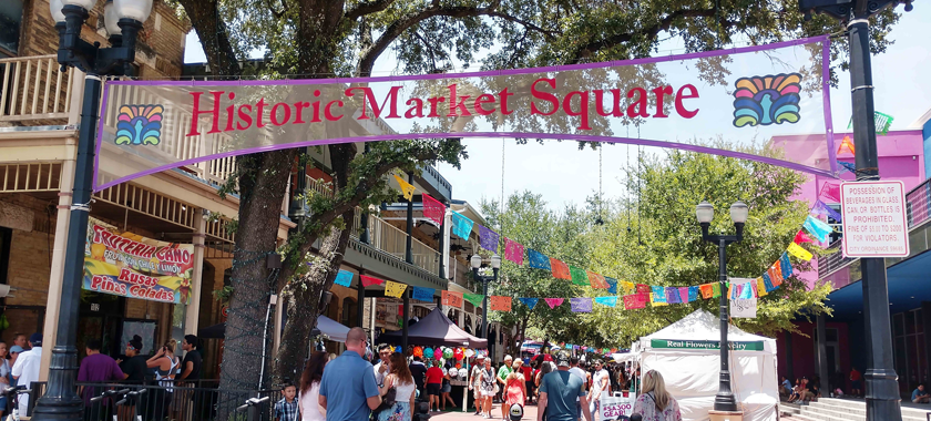 Image Detail: A bustling thoroughfare with tents and members of the public passing through; there is a banner with "Historic Market Square" in the center of the image