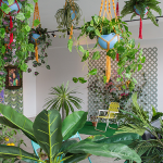 Image: Tiffany Smith (Fellow in Interdisciplinary Work ’18), Plant Life (Installation view), 2017, Multimedia installation with interactive photo set. On the wall to the left, there are framed photographs, video on monitor, and custom designed wallpaper. The rest of the room is filled with live and artificial plants, macrame plant hangers, readymade furniture pieces and garden decor items.