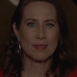 Close up film still of Miriam Shor as Harriet, with red dress and red lipstick, nervous and excited, in a cinema in "MAGIC HOUR"