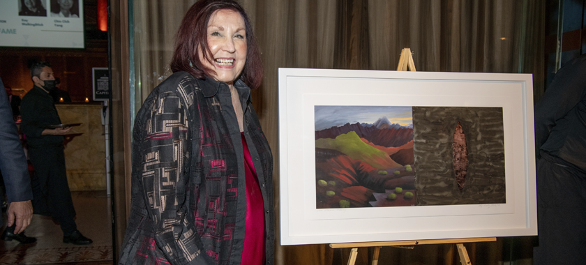 Kay WalkingStick smiling and posing with her artwork "Havasu Revisited"