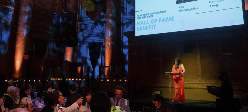 Angela Henry onstage in a bright orange gown at NYFA's 2022 Hall of Fame Benefit