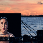 Photograph of "Night Watch," a floating installation that circulated in NYC’s waterways during Fall 2018. The artwork featured a 20ft-wide LED-screen which travelled the city’s waterways aboard a large, slow-moving barge and tug boat.