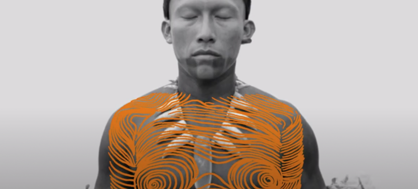 an indigenous man in black and white is overlayed with a bright orange drawing that looks like a topographical torso of a female
