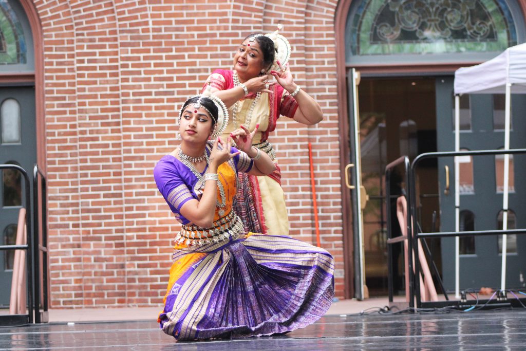 Two individuals wearing in traditional Indian clothing are still in a dance gesture.