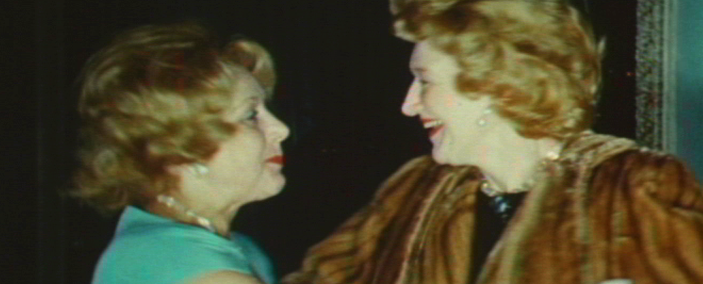 Video still of two women with blonde hair arms out going into an embrace