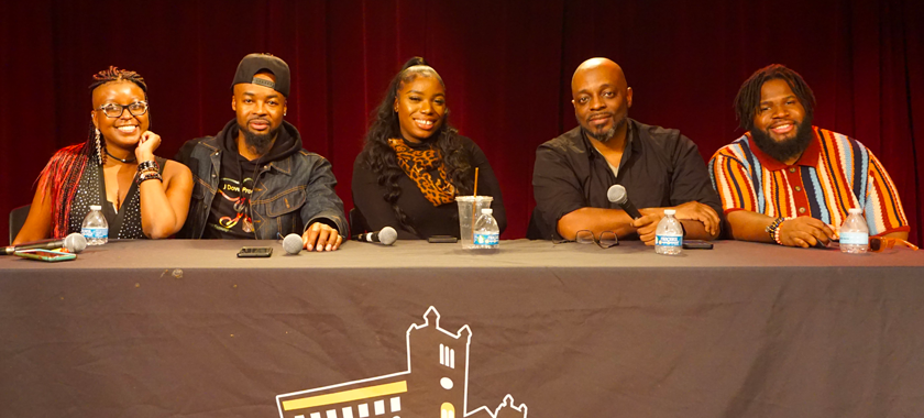 5 People smiling seated at a table with a black table cloth on it that reads JCAL 50.