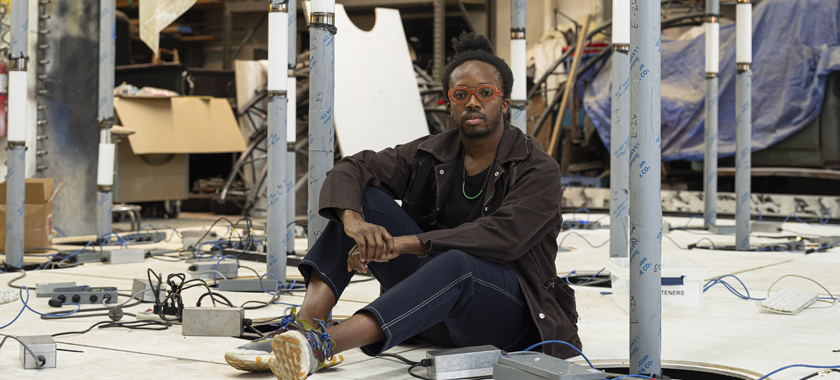 Shot of Nigerian-American man sitting in the middle of 10s of light poles