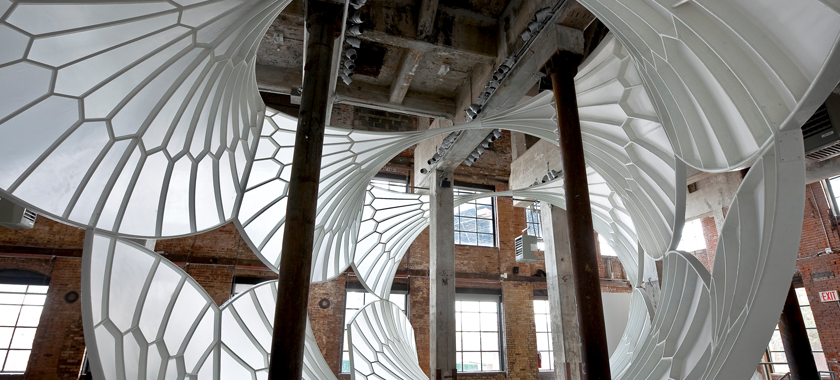 A light, airy, cathedral-like structure installed in a tall industrial space.