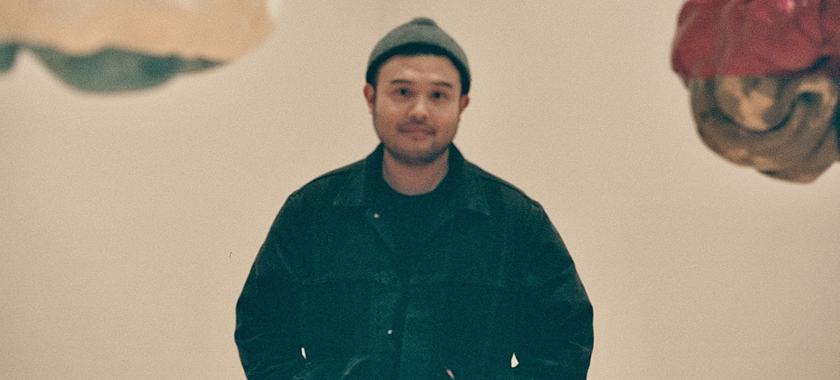 Blurry analog-looking photo of Dan Bamba in front of two artworks