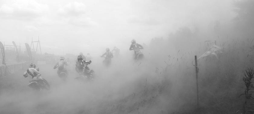 Black and white photograph of dirt bikes kicking up dust at the start of a hare scramble race in West Virginia.