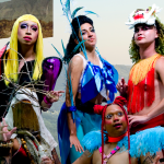 Five colorfully dressed ensemble members from a performance called "TERRITORY: The Island Remembers" pose in shimmering costumes, wigs, and make up. A few give fierce looks to the camera lens standing and kneeling in front of a background of a collage featuring mountains, lush green hills, trees, and other vegetation.