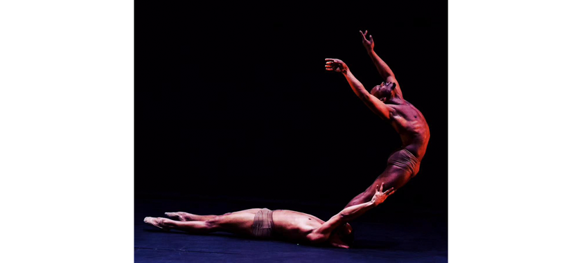 Two dancers photographed against a dramatic black background