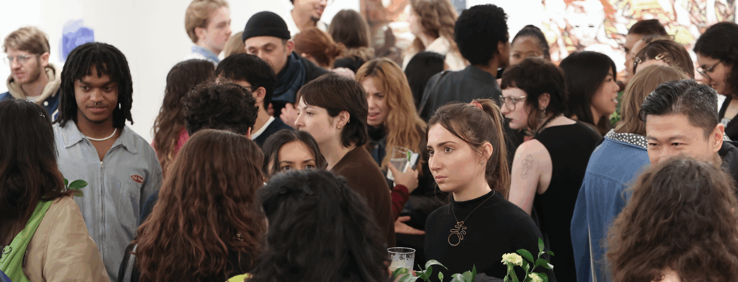 Young people gather for an IMPULSE Magazine benefit exhibition in what looks to be a crowded gallery space