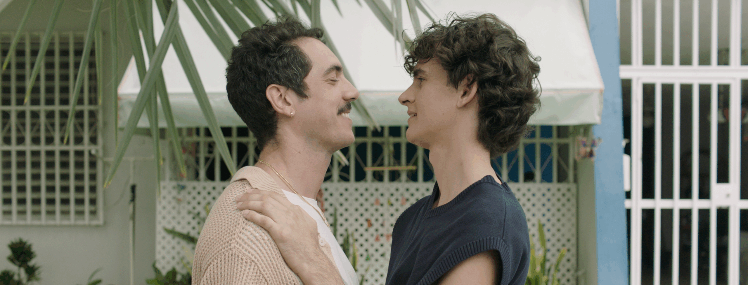 Film characters Mateo and Gael embrace in front of Abuela Nina's house. They are holding each other in their arms and are filled with a mix of sadness and happiness of their time together.