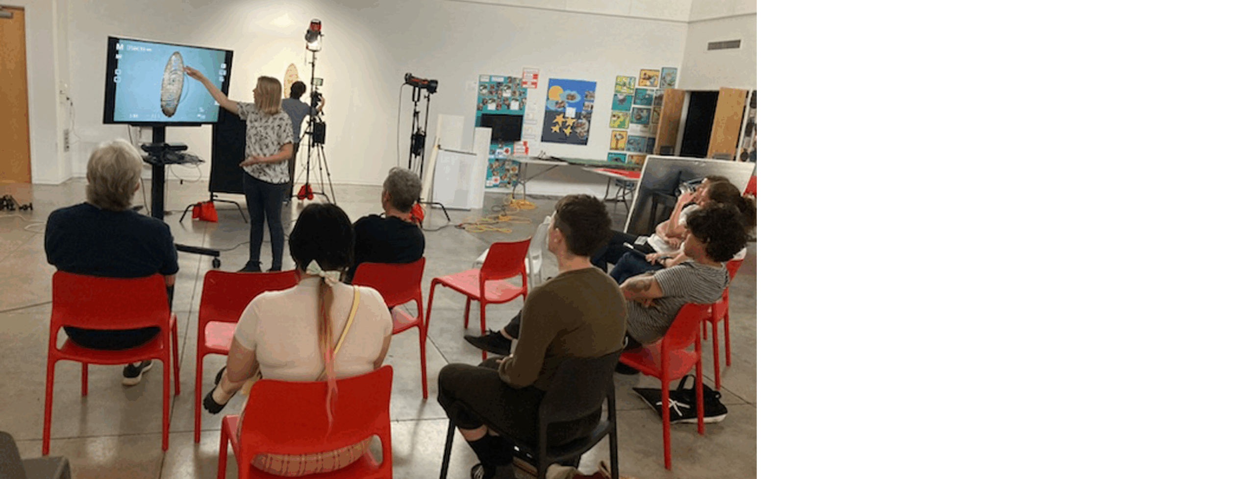 An individual stands in front of a small group of seats artists, pointing at a monitor as part of a professional development workshop