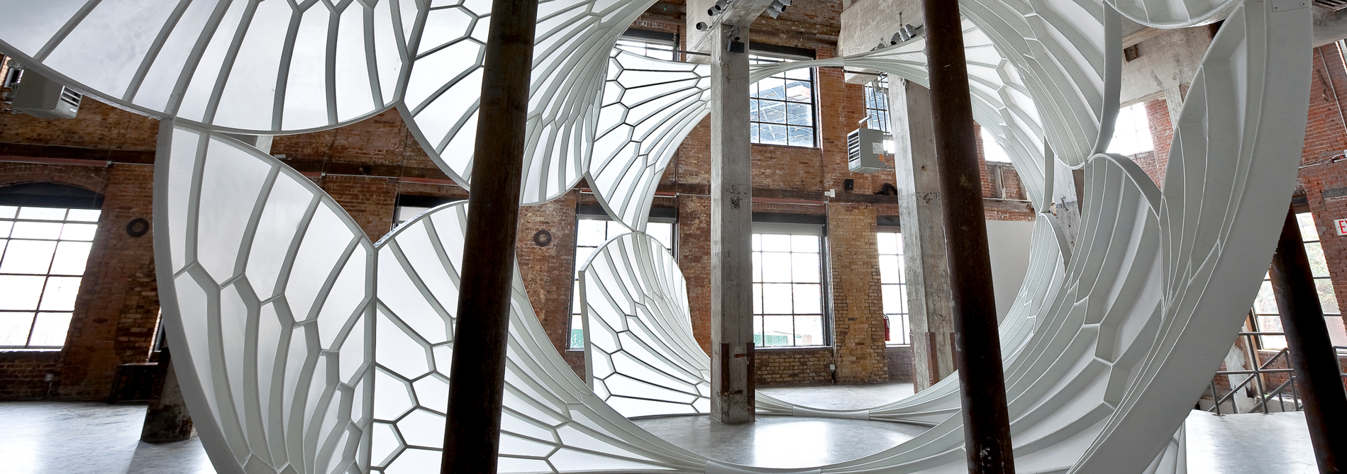A light, airy, cathedral-like structure installed in a tall industrial space.