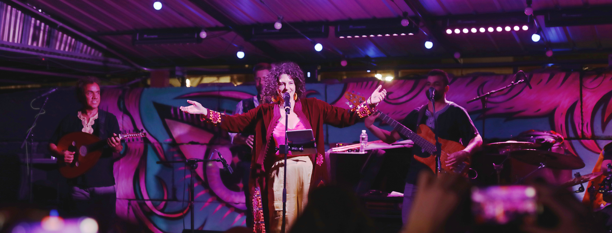 A band singing on a pink outdoor stage.