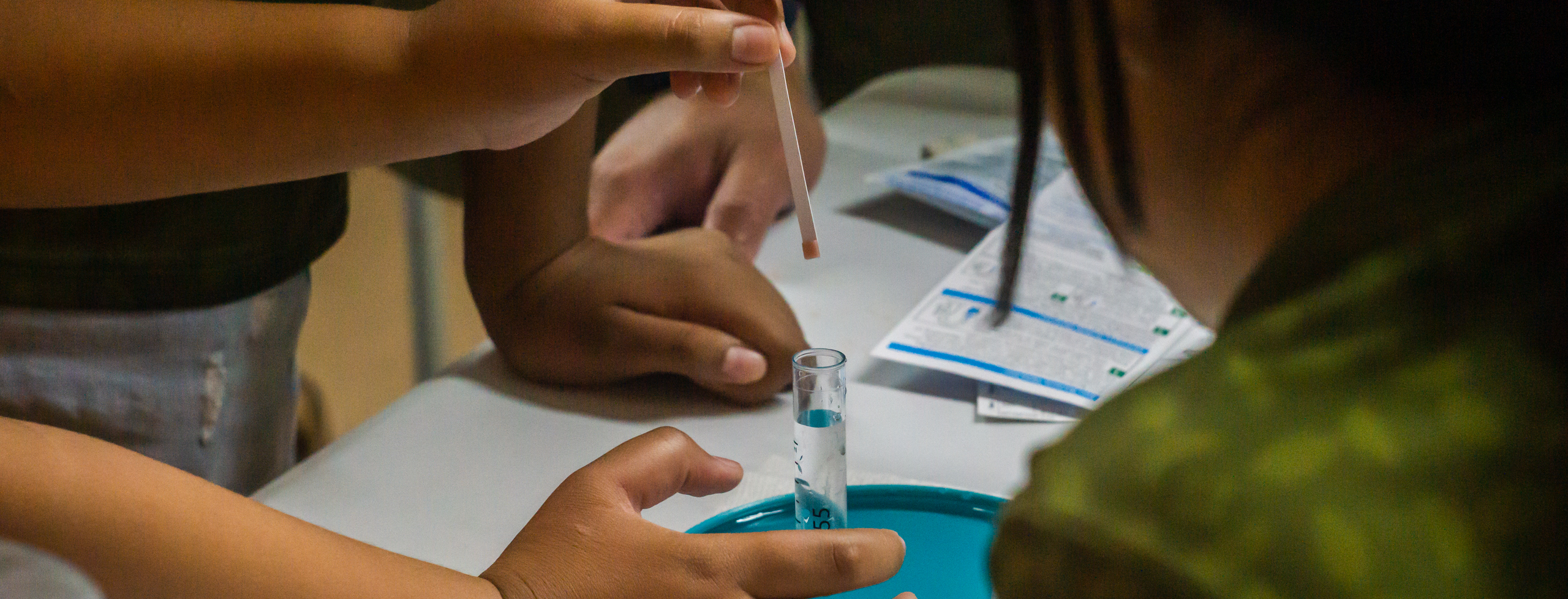 A zoomed in shot of a child's hands holding a water test strip