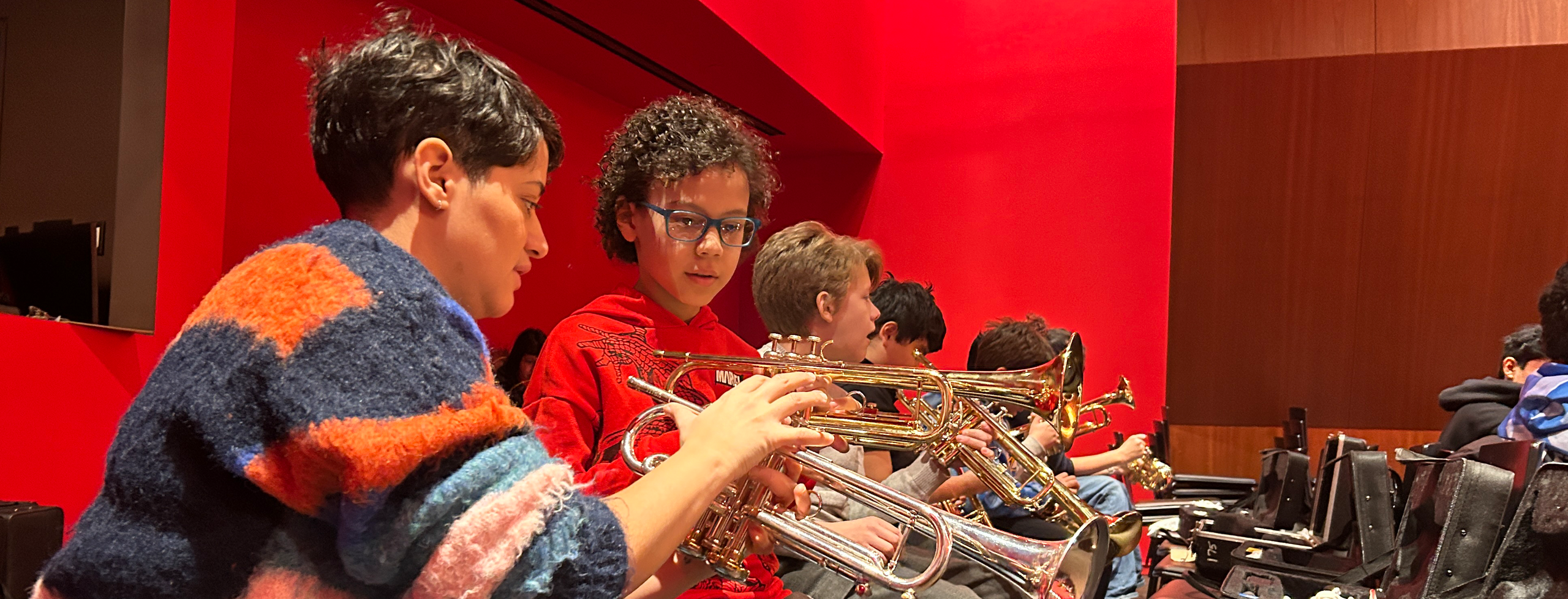 A teaching artist gives a trumpet lesson to a group of young students at the Louis Armstrong House Museum