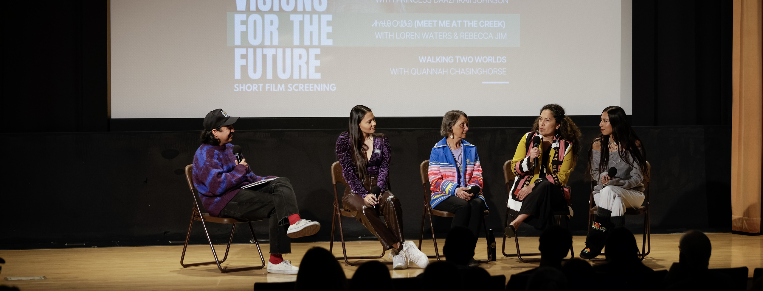 Image from a panel discussion after a film screening, five people on stage with microphones