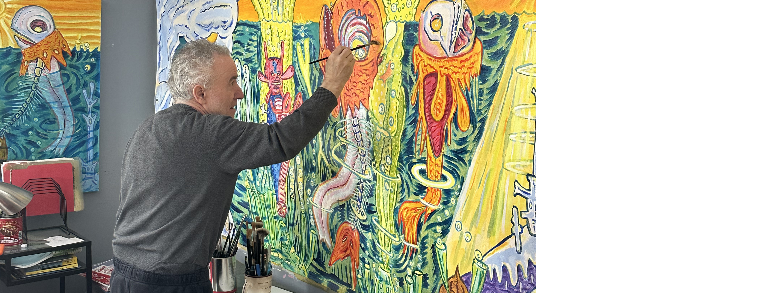 Artist David Sandlin painting in his winter studio in the Catskills, with silkscreened prints of same image.