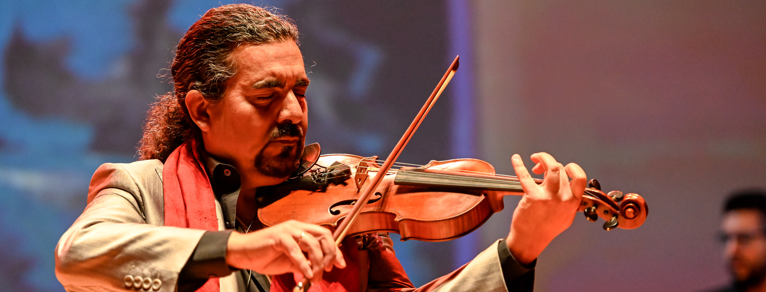 A man closes his eyes in as he plays a violin