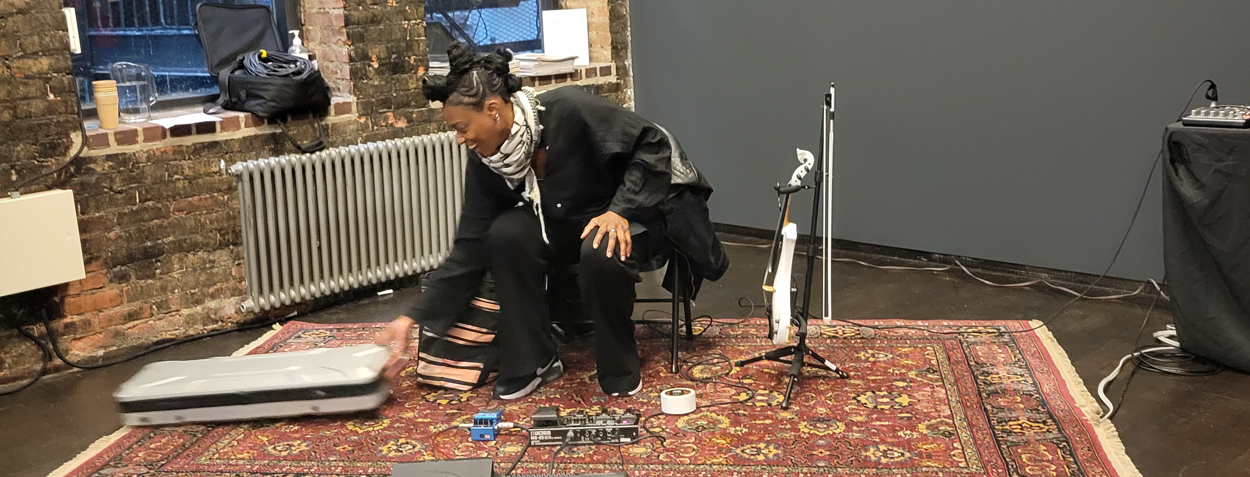 Dressed in all black and of African ancestry,Violinist Joya Bravo is seated assembling all that is needed for amplifying her music.