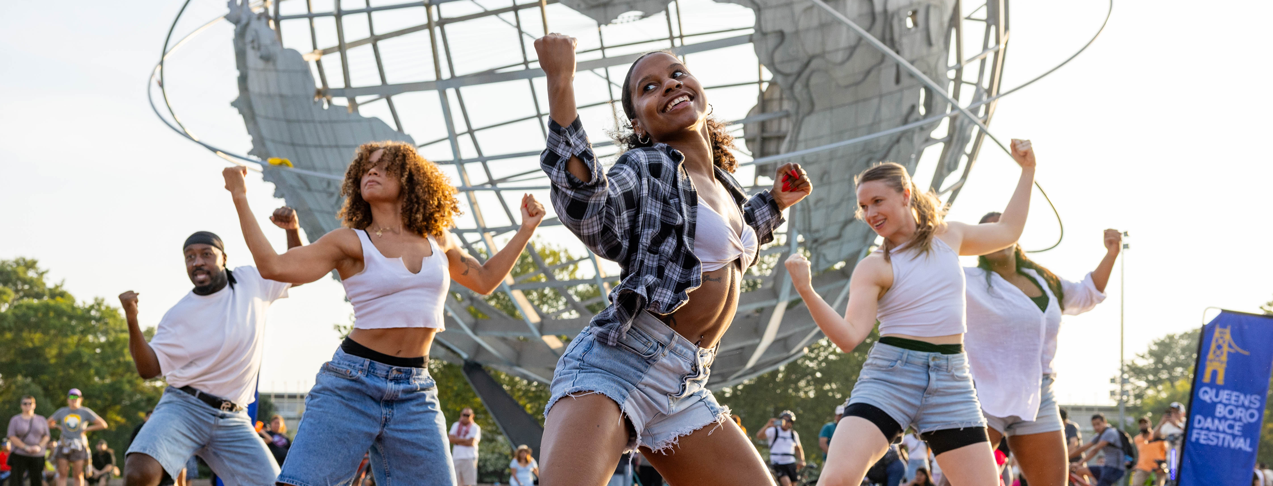 Dancers performing outdoors wearing white shirts, black accessories, and denim