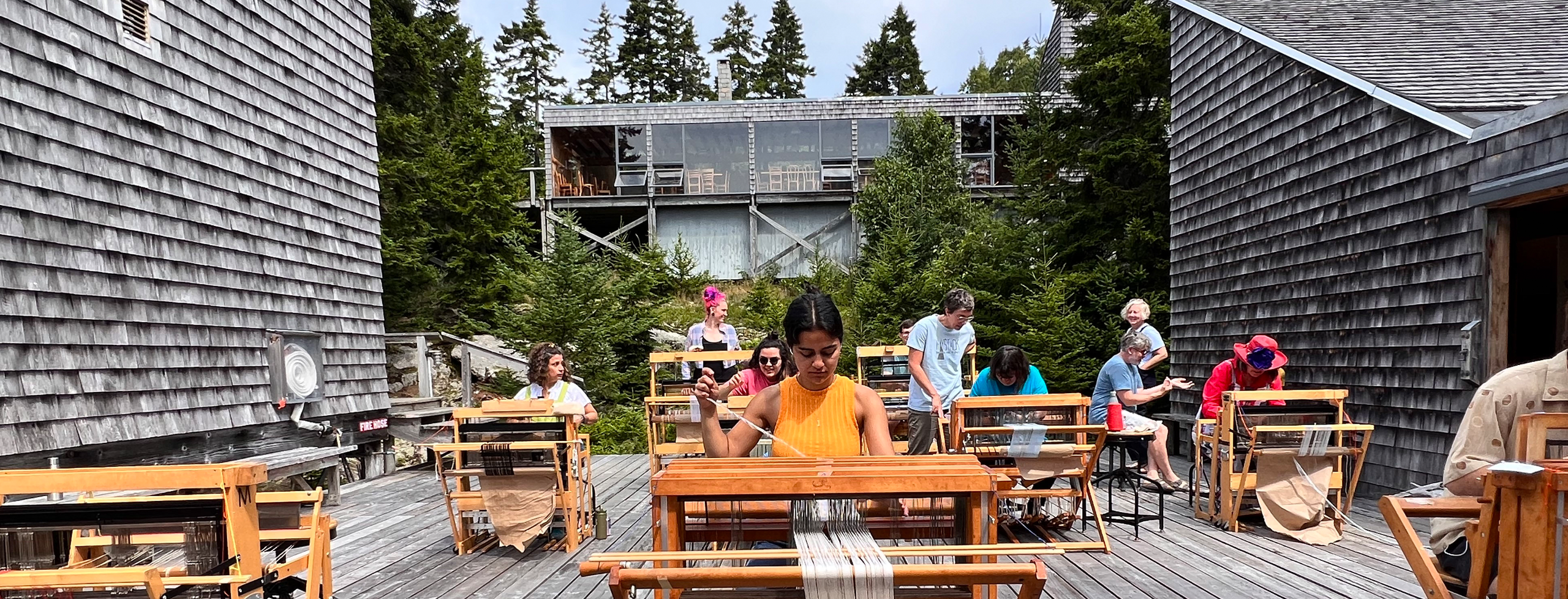 Students move their looms onto the deck outside the Fiber studio to enjoy the sunshine on the Haystack campus