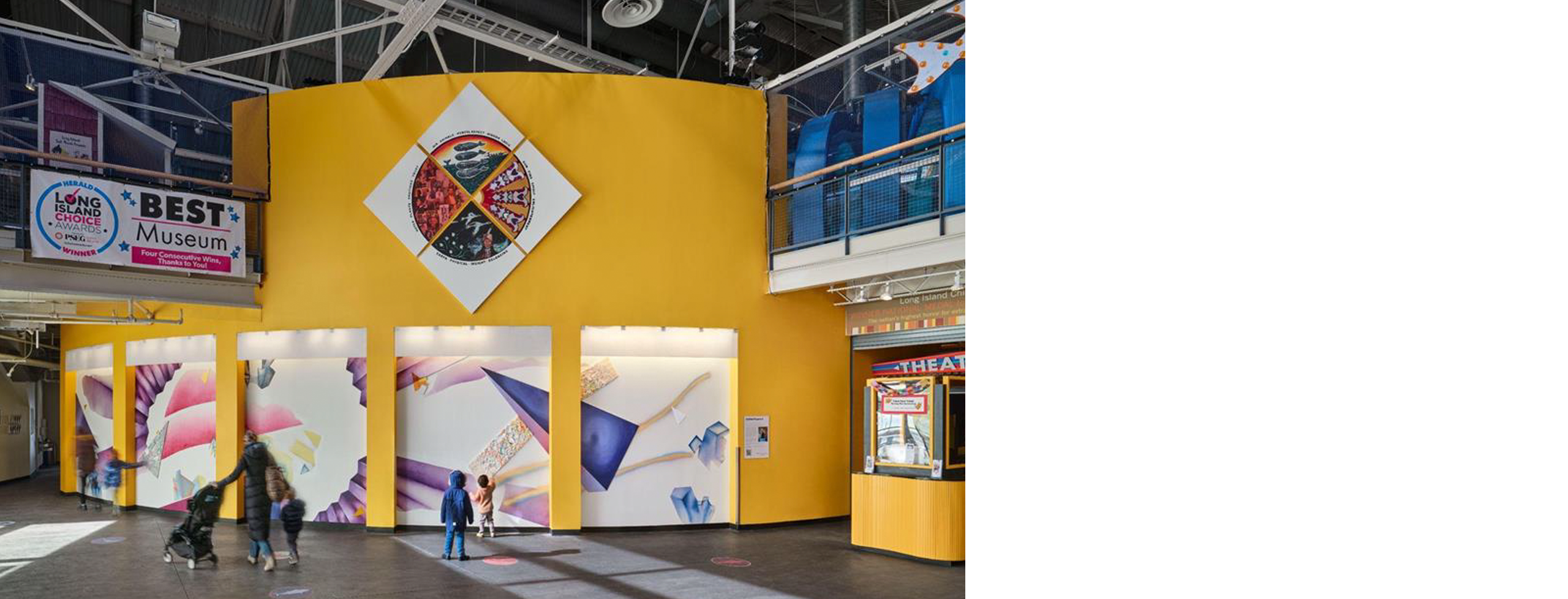 Installation shot of an airy, high ceiling space at Long Island Children's Museum, Kelly Olshan's work dynamically displayed in panels on a curving wall.