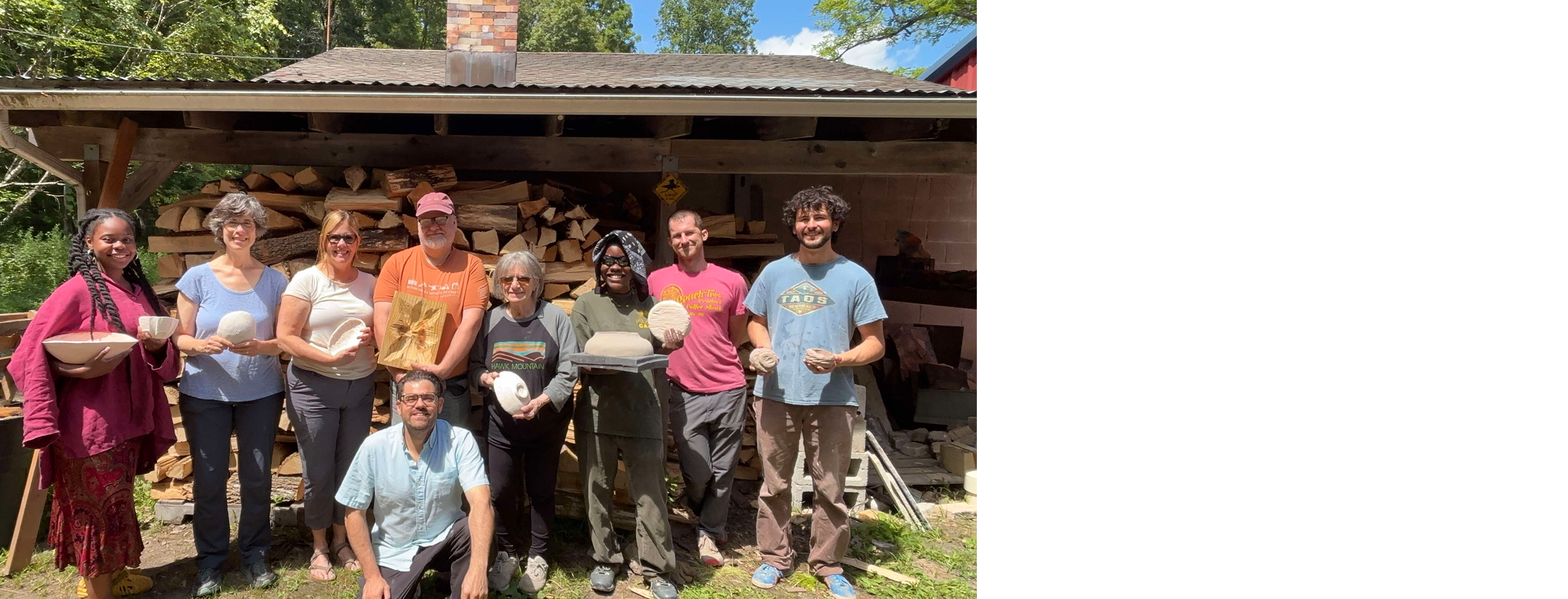 A group of people holding ceramics made from slump molds pose for the camera