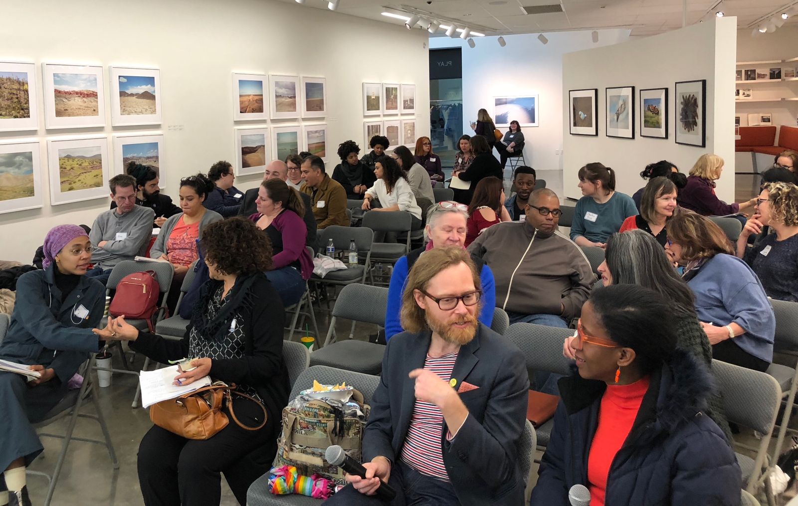 People talking animatedly while seated in a gallery space