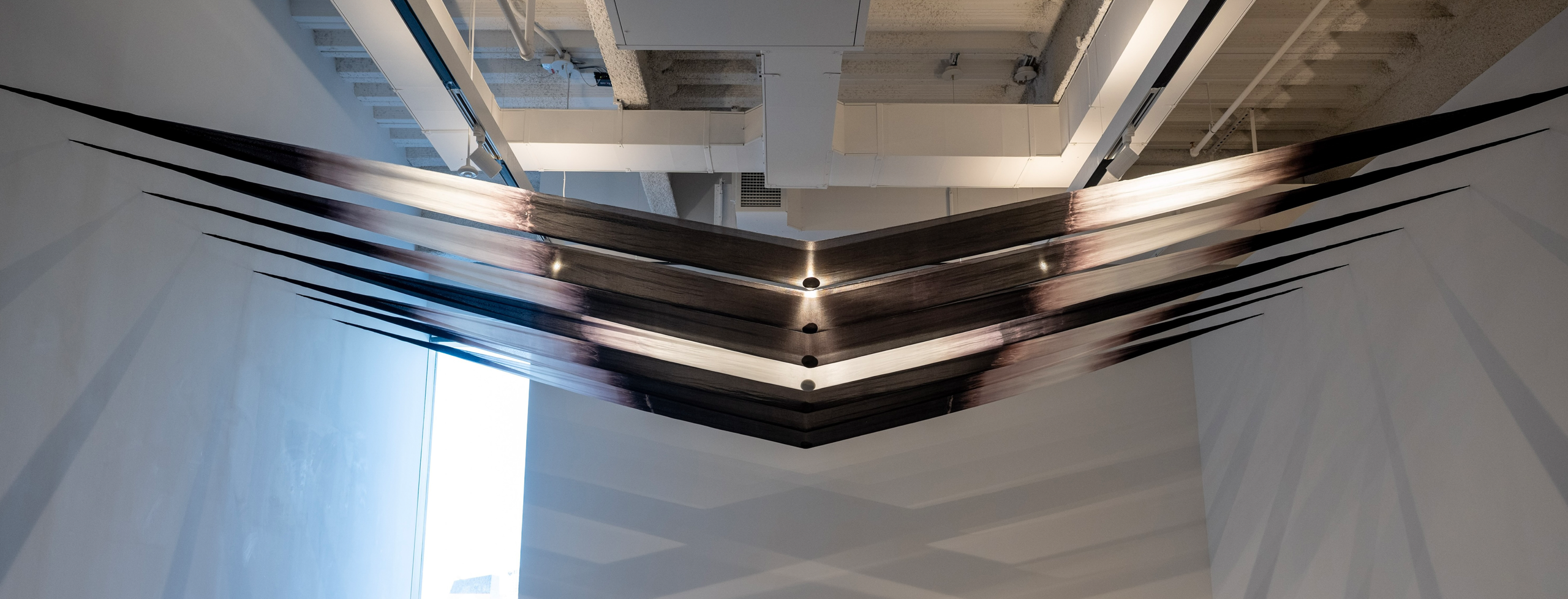 dyed sik weighted ny rocks, dramatically suspended from two sides of a gallery wall