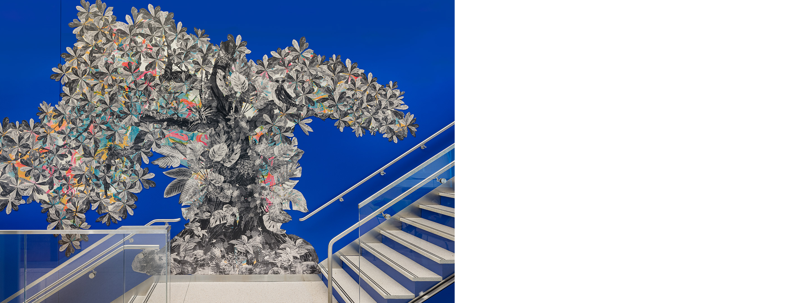 Alt Text: Photograph of a large-scale public art mural installed above a stairwell, painted or applied directly onto a vivid cobalt-blue wall.